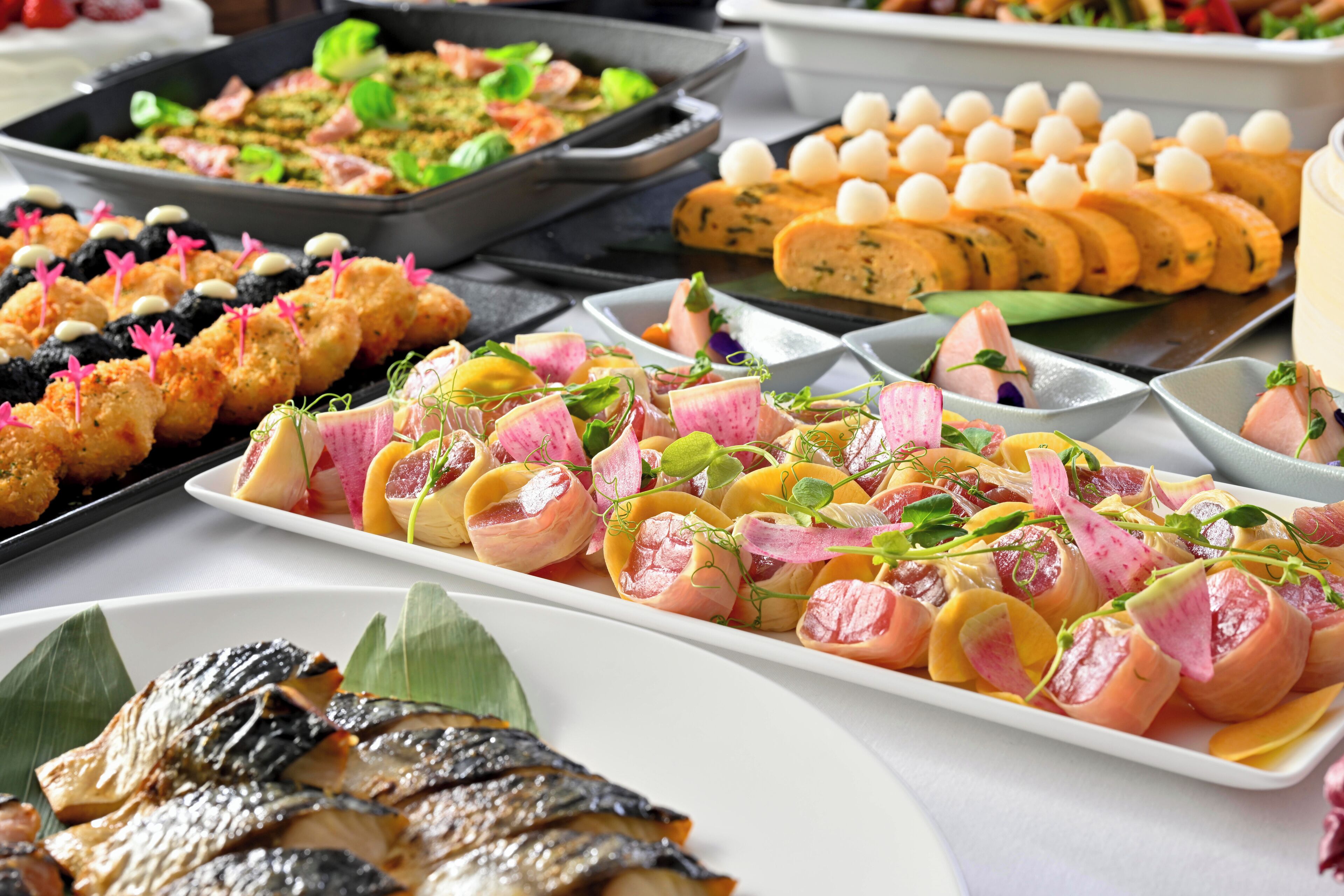 Un buffet proposant divers plats, notamment des brochettes, de la viande enroulée et un assortiment de salades.