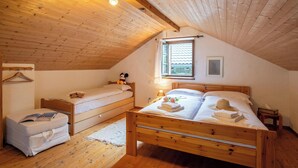 Et hyggeligt soveværelse i skunken med skrå træloft, to senge, et lille natbord, en hængende lampe og et vindue med udsigt.