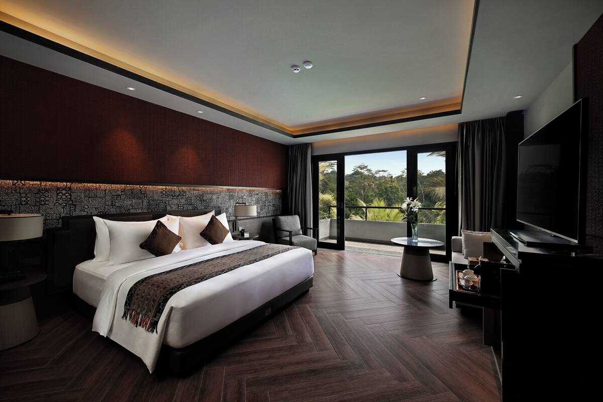 A modern hotel room with a large bed, a flat-screen TV, a balcony with a view, and a large window.