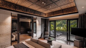 A modern hotel room with a large bed, a seating area, a TV, and a balcony with a view of the outdoors. - Ayatara Resort Ubud  (Kerta)