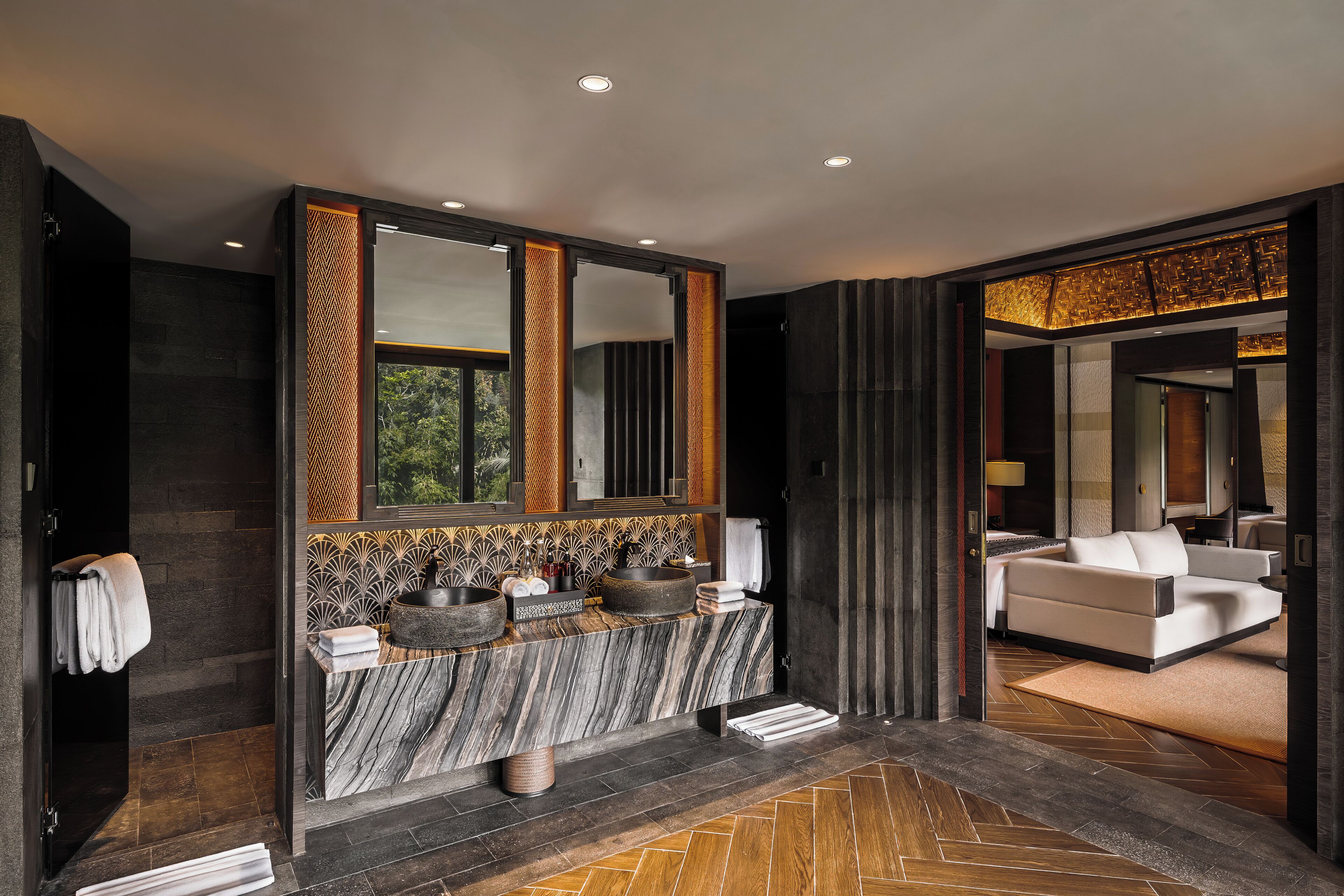 Casa de banho moderna com toucador de mármore, espelhos grandes e chão em padrão herringbone.