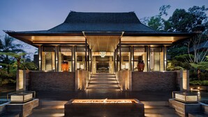 A modern building with a traditional roof, a central fire feature, and a pathway leading to the entrance. - Ayatara Resort Ubud  (Kerta)
