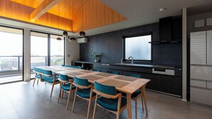 Une cuisine moderne avec une grande table à manger, des chaises de couleur turquoise et une vue sur la ville.