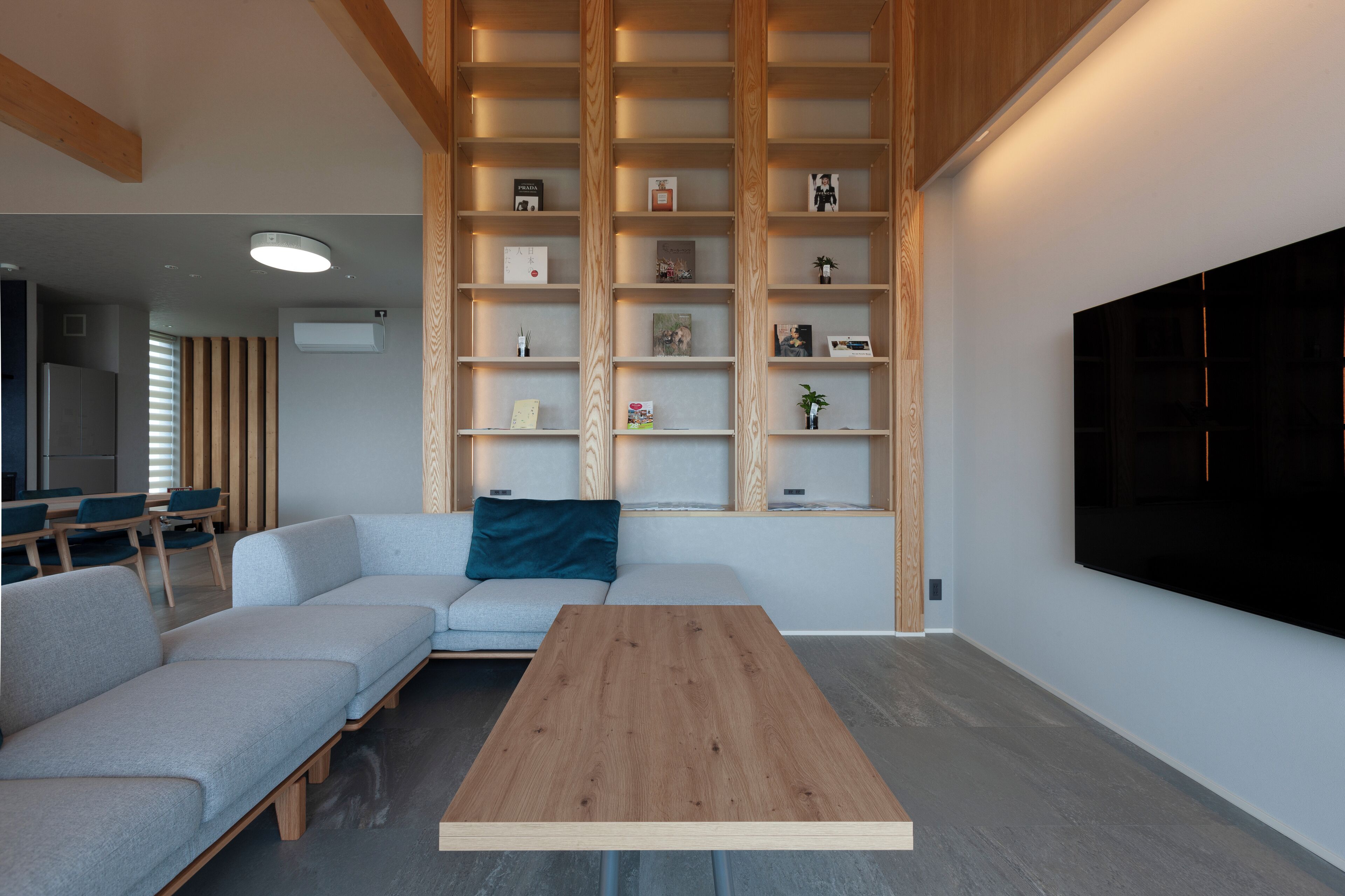 A modern living room with a sectional sofa, a wooden coffee table, and built-in shelving with various items.