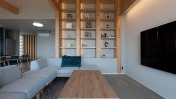 A modern living room with a sectional sofa, a wooden coffee table, and built-in shelving with various items.