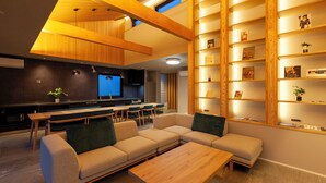 Un salon moderne avec un canapé d’angle, une table basse en bois et des étagères intégrées ornées d’objets décoratifs.