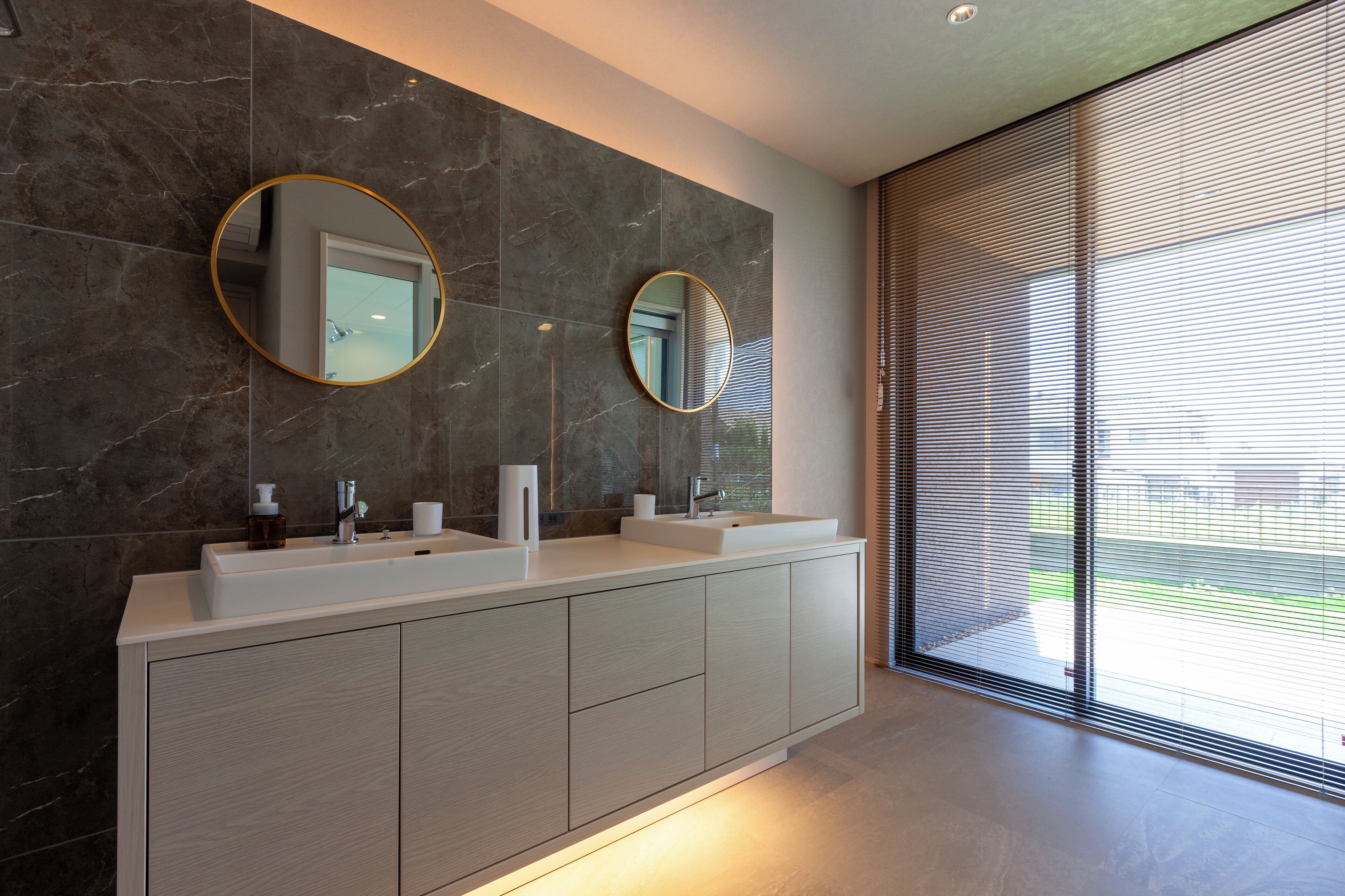 A modern bathroom with two sinks, a large mirror, and a sliding glass door leading to a balcony.