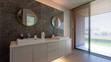 A modern bathroom with two sinks, a large mirror, and a sliding glass door leading to a balcony.