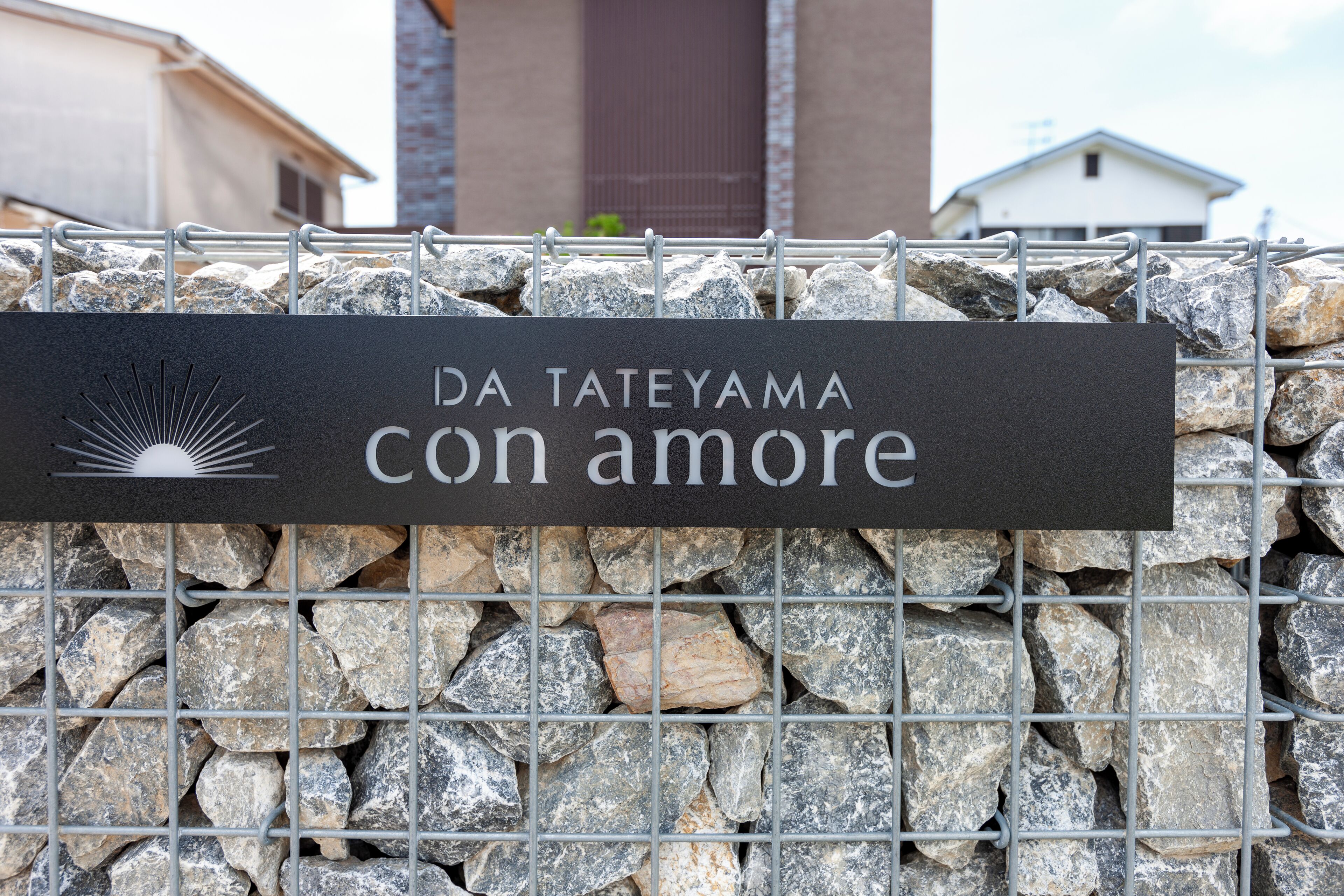 Un muro di pietra con un cancello in metallo e un cartello che recita 'DA TATEYAMA con amore'.