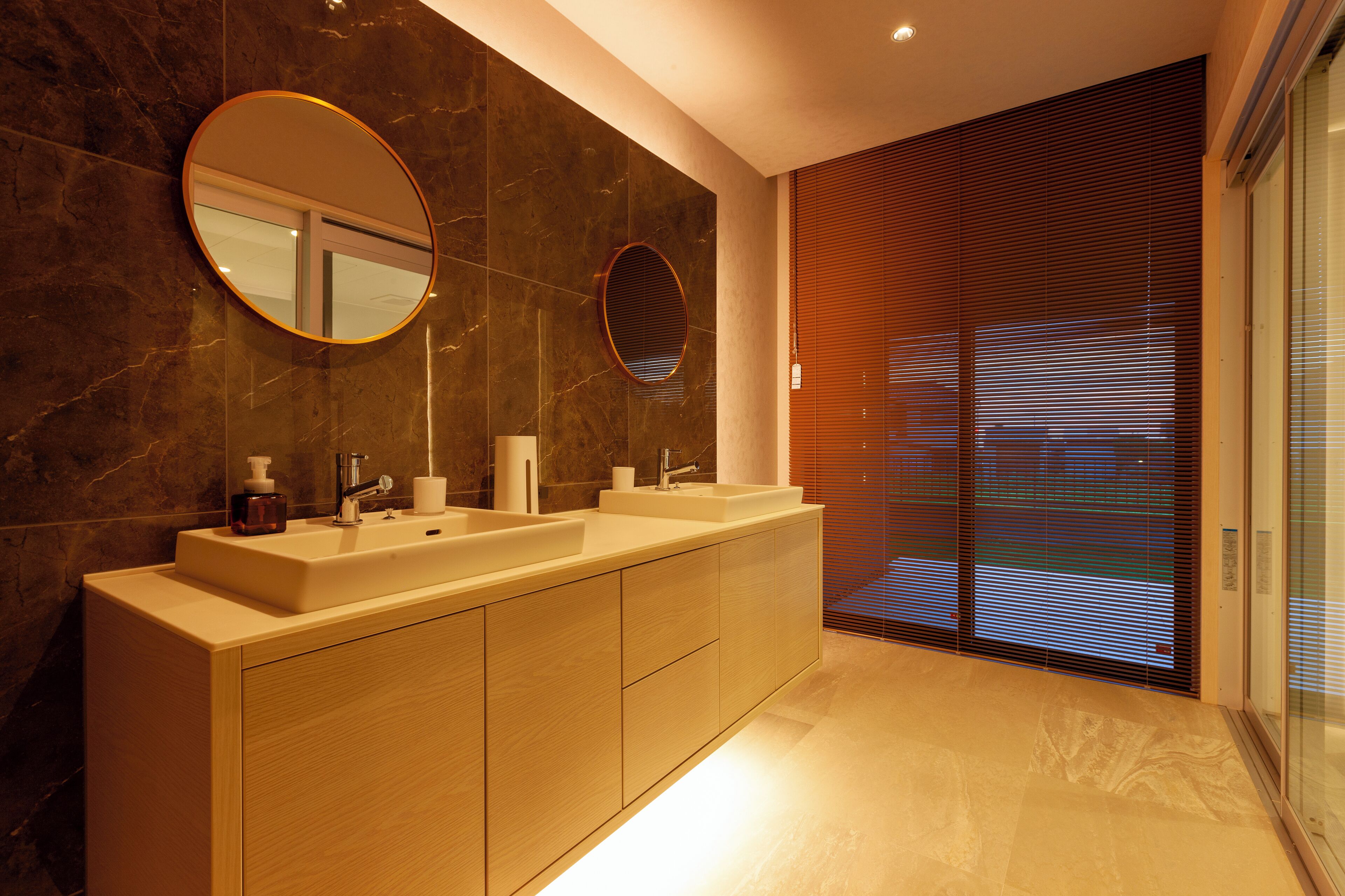 Un bagno moderno con due lavabi, uno specchio grande e una porta in vetro che dà su un balcone.