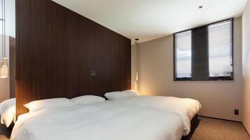 A bedroom with a large bed, wooden panel wall, and a window with blinds.