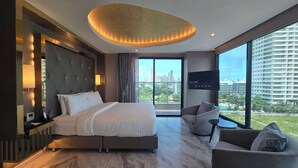 Una habitación de hotel moderna con una cama grande, un sofá, un televisor y vistas a la ciudad.