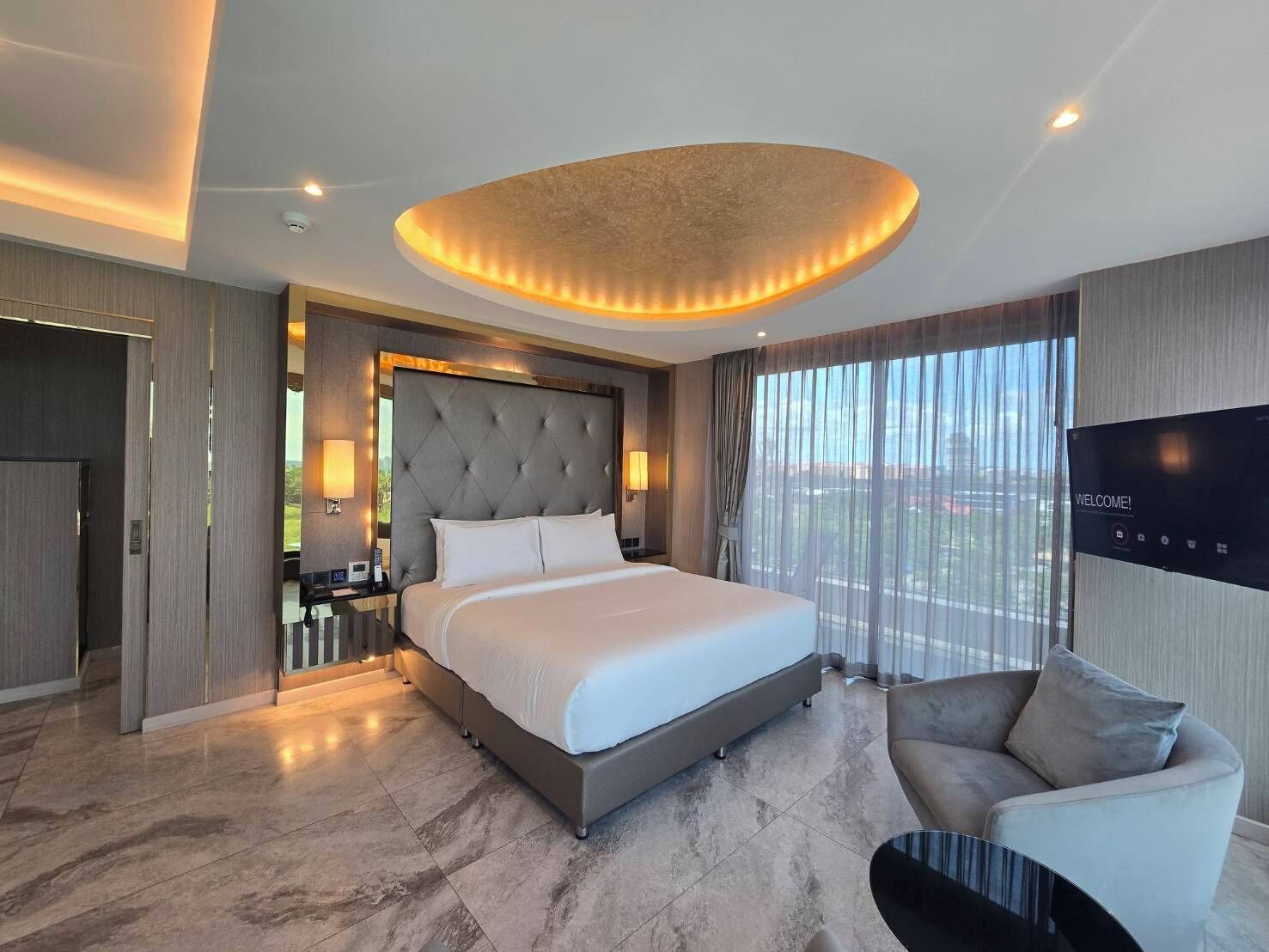 Une chambre d’hôtel moderne avec un grand lit, un canapé, une télévision et une vue sur la ville.