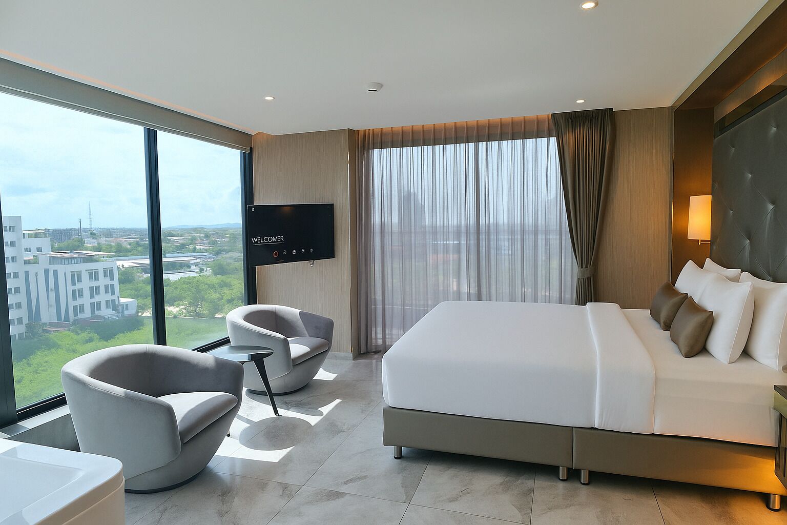 A modern hotel room with a large bed, two armchairs, a TV, and a city view.