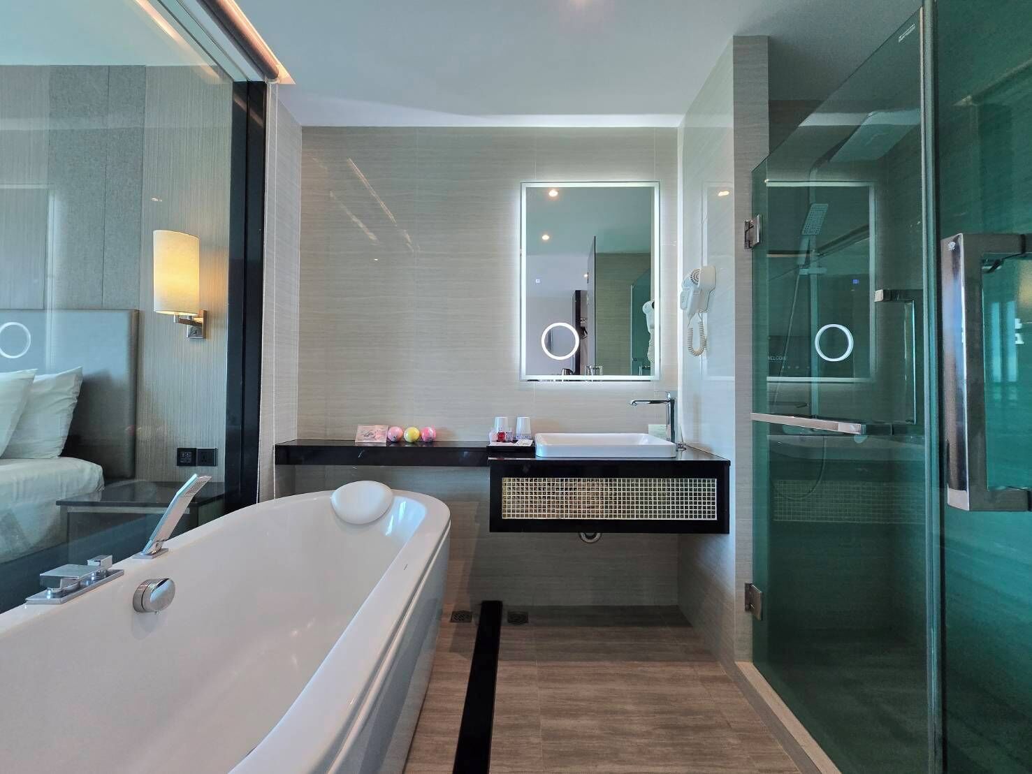 A modern bathroom with a large bathtub, a vanity with a mirror, and a glass shower enclosure.
