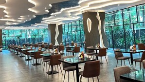 Un restaurante moderno con un diseño de techo singular, ventanas amplias y una distribución espaciosa.