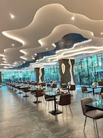 Un restaurante moderno con un diseño de techo singular, ventanas amplias y una distribución espaciosa.