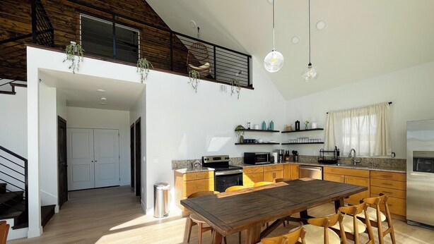 Une cuisine spacieuse avec des meubles en bois, une table à manger et des plantes suspendues.