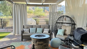 An outdoor patio with a stone fire table, wicker furniture, and a view of the mountains. - Beautiful home on Golf Course in gated community centrally located in Phoenix.  (Phoenix)