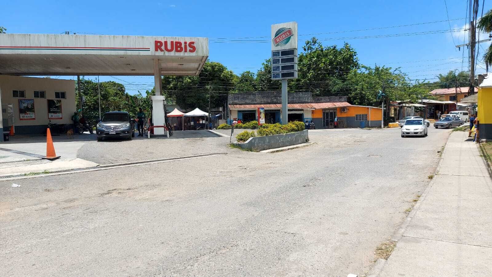 Une station-service avec une enseigne « RUBIS », un petit bâtiment avec un toit rouge et une voiture garée.