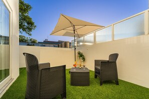 A patio with wicker furniture, a table, and an umbrella. - GuestReady - Peaceful home with a private backyard (Porto)