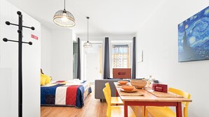 A modern hotel room with a bed, a dining area with a table and chairs, a painting on the wall, and a sign indicating the room is ready for guests. - GuestReady - Peaceful home with a private patio (Porto)