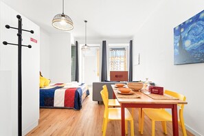 A modern hotel room with a bed, a dining area with a table and chairs, a painting on the wall, and a sign indicating the room is ready for guests. - GuestReady - Peaceful home with a private patio (Porto)