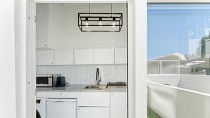 A compact kitchen with white cabinets, a built-in microwave, a coffee maker, and a dishwasher. - GuestReady - Peaceful home with a private patio (Porto)