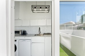 A compact kitchen with white cabinets, a built-in microwave, a coffee maker, and a dishwasher. - GuestReady - Peaceful home with a private patio (Porto)