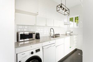 Cocina compacta equipada con microondas, cafetera, pileta y lavadora.
