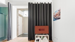 A hotel room with a large window, a flat-screen TV, a small table with a remote, and a door leading to a bathroom. - GuestReady - Peaceful home with a private patio (Porto)