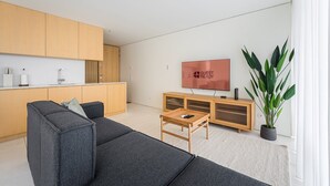 A modern living room with a sofa, a coffee table, a TV, and a plant.