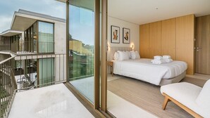 A modern hotel room with a balcony, a large bed, and a wooden wardrobe.