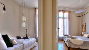 A modern bedroom with two beds, a sofa, and a mirror.