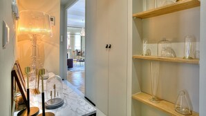 A hallway with a marble floor, a lamp, and glassware on shelves.