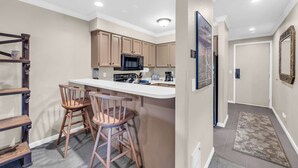 Una cocina moderna con una isla central, sillas de madera y un microondas.