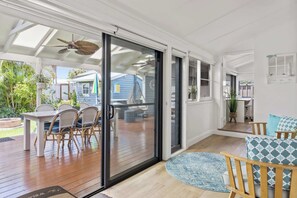A patio with a table and chairs, a ceiling fan, and a view of the backyard. - Spa & Chill Lodge Budgewoi 3BR (Budgewoi)