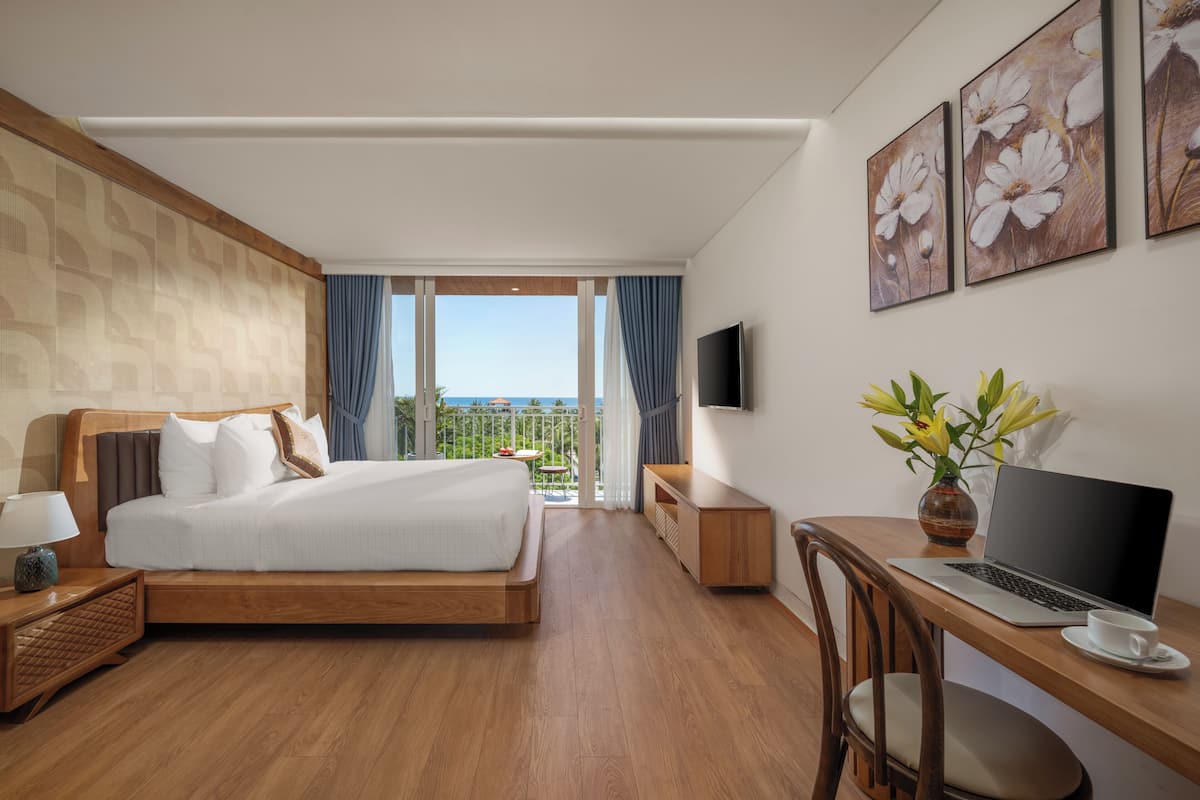 Une chambre d’hôtel avec un lit, un bureau avec un ordinateur portable, une télévision et une vue sur l’extérieur.