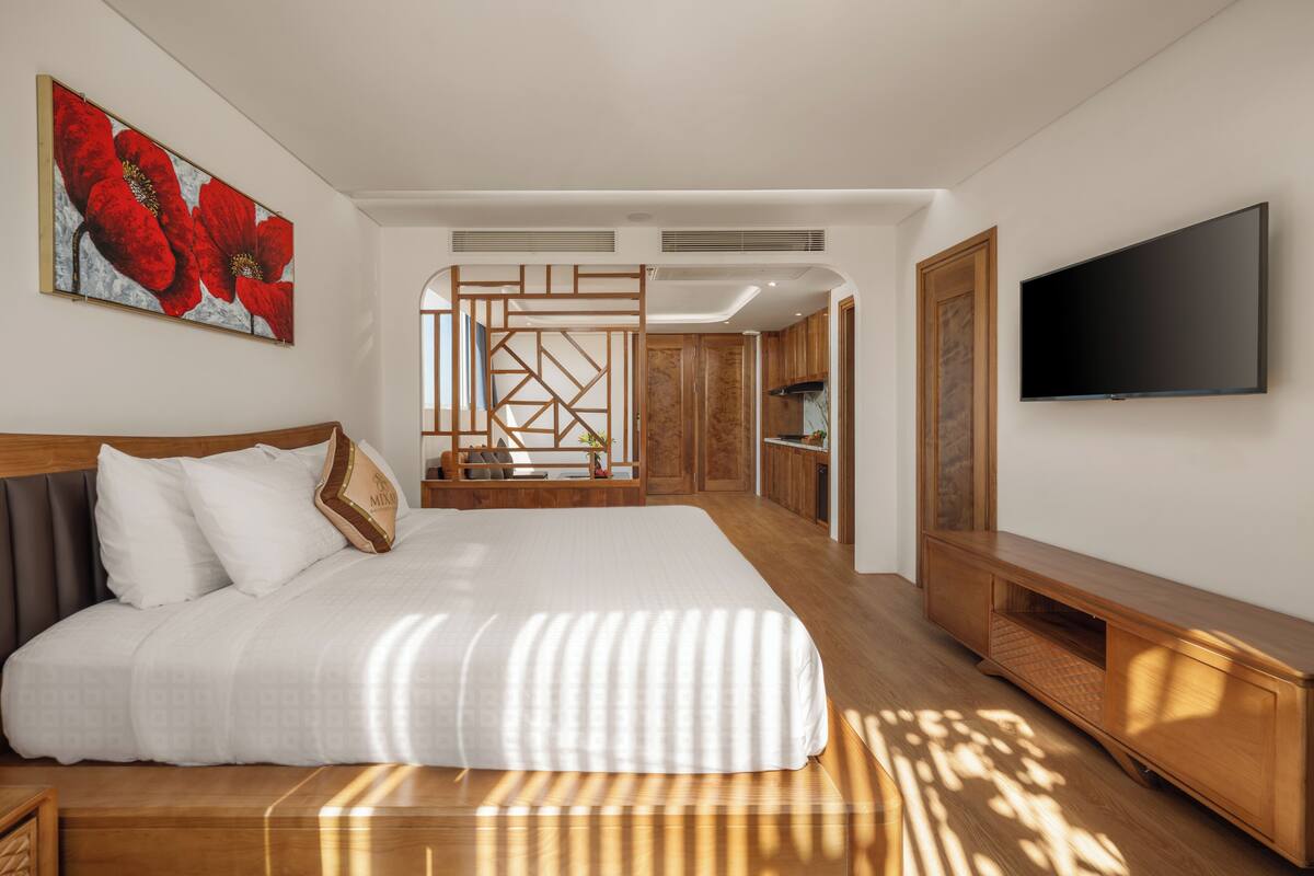 Une chambre d’hôtel moderne avec un grand lit, une télévision et un plancher en bois.