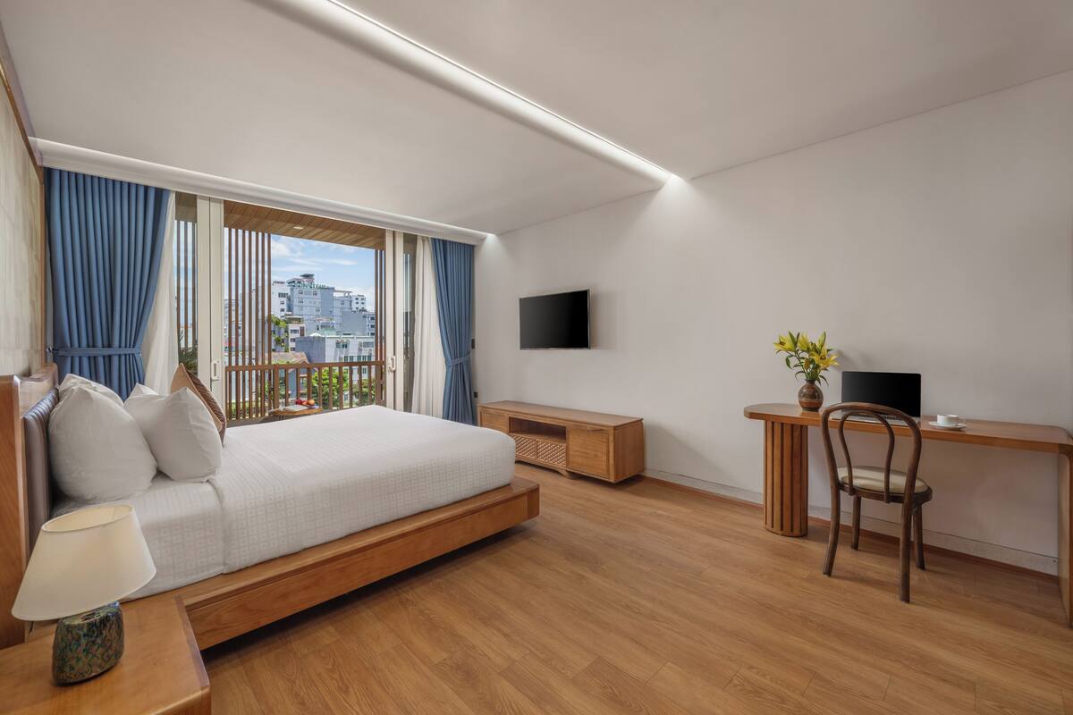 Une chambre d’hôtel moderne équipée d’un lit, d’un bureau, d’une chaise, d’une télévision et offrant une vue sur la ville.