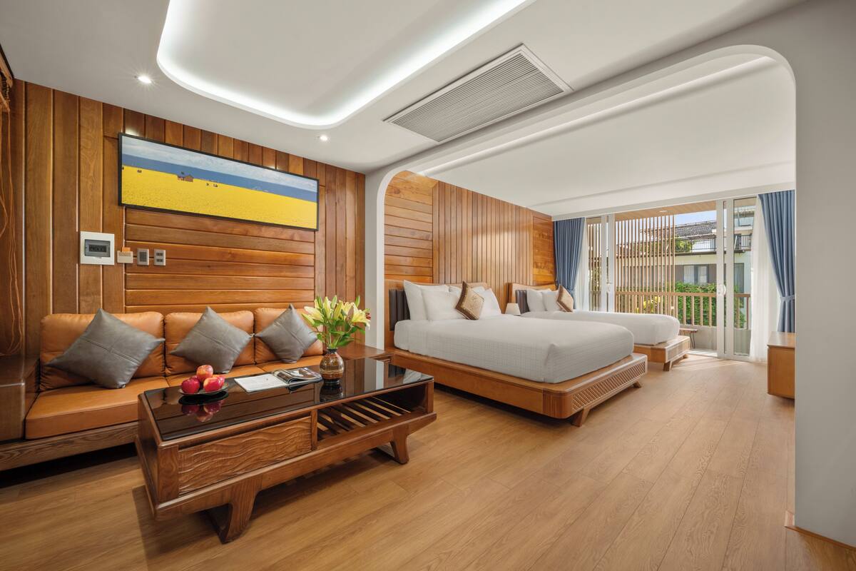 Une chambre d’hôtel moderne avec un mur lambrissé en bois, un grand lit, un canapé et une table basse en verre.