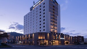 A multi-story hotel with a modern design, featuring a prominent sign at the top and a well-lit entrance. - Hotel Enoe Hakodate (Hakodate)