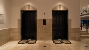 A hotel lobby with two dark wooden doors, a tiled floor, and a small sign above the doors. - Hotel Enoe Hakodate (Hakodate)