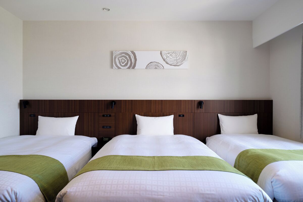 A hotel room with two beds, a wooden headboard, and a wall-mounted artwork.