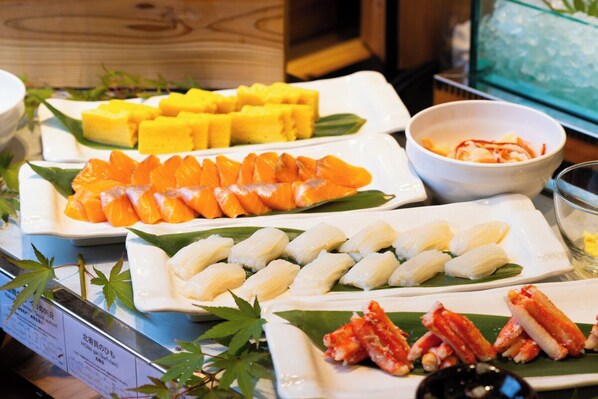 Variedad de platos de sushi sobre una mesa, incluyendo salmón, jengibre amarillo encurtido y otros mariscos.