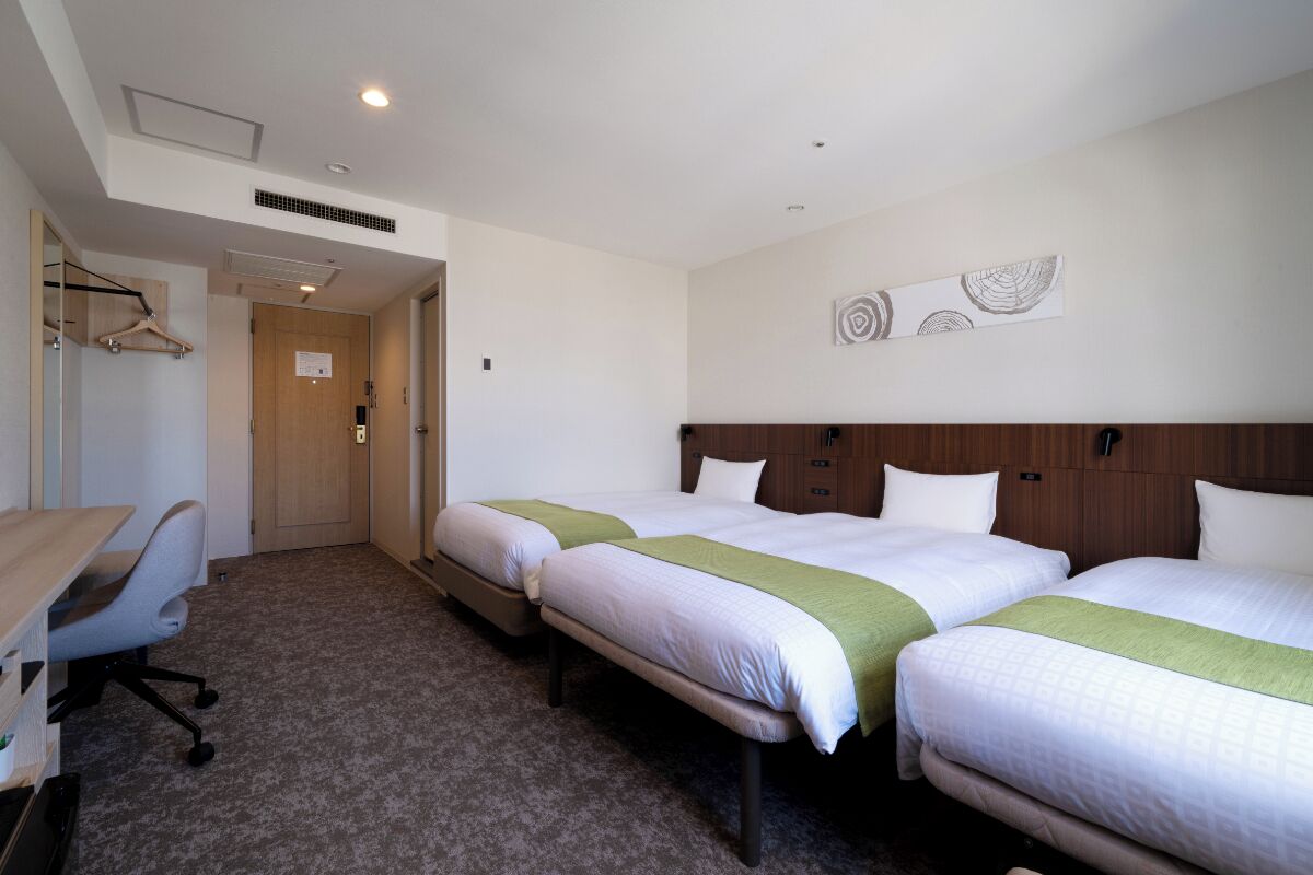 A hotel room with two beds, a desk, and a chair.