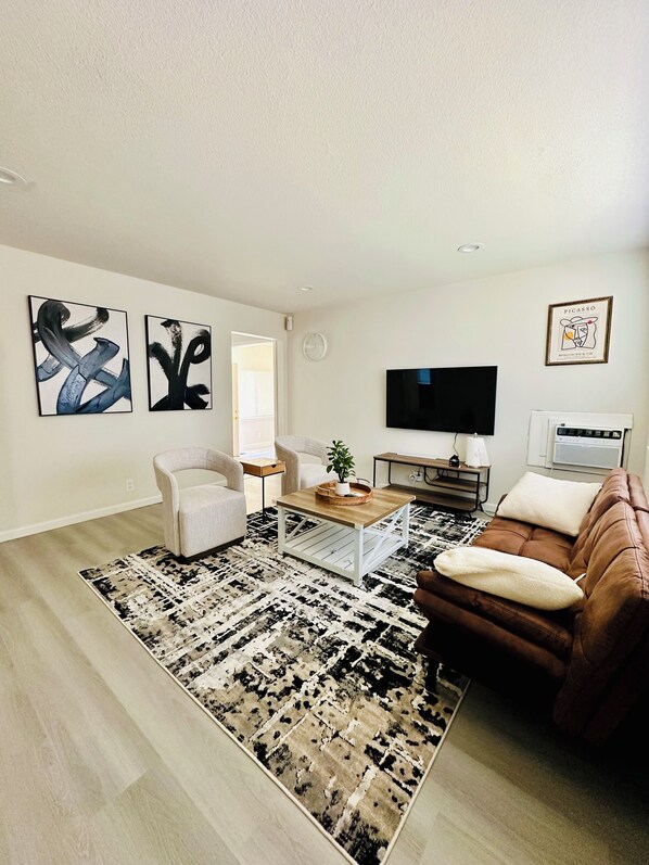 Uma sala de estar com design moderno, com um sofá, poltronas, uma mesa de centro e obras de arte nas paredes.