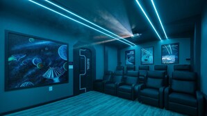 Ein Kino mit großer Leinwand, Liegesesseln und einem Wandgemälde zum Thema Weltall.