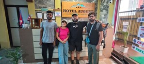 Un área de recepción con un cartel que dice 'HOTEL AUGUST INTERNATIONAL' y un cartel que indica 'HORA DE SALIDA 12:00 MEDIODÍA'.