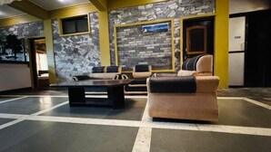 A lobby with stone walls, a reception desk, and seating areas. - Hotel August International (Pokhara)